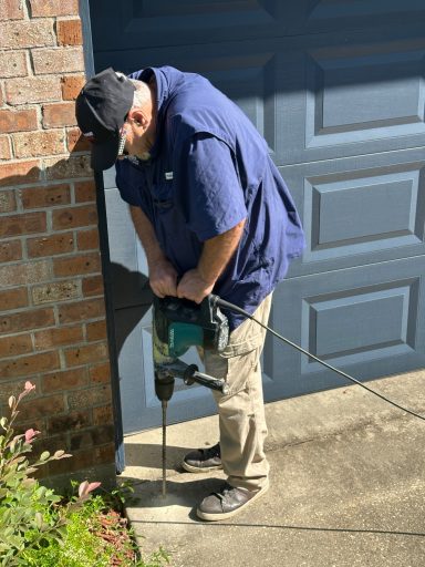 Professional Termite Treatment Installation Technician drilling beside a home's foundation to perform a professional termite treatment.