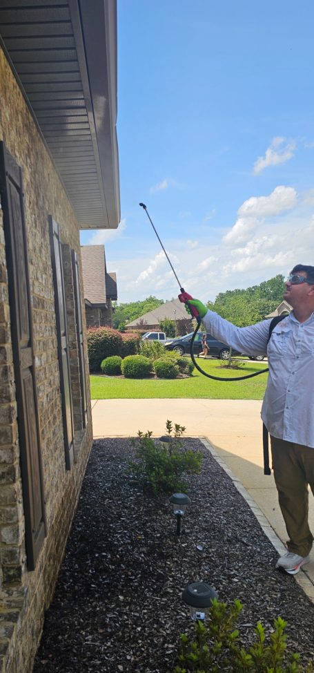 Exterior Pest Control Treatment Around Home Hilbun Pest Control technician using a backpack sprayer to treat underneath the eaves of a home.
